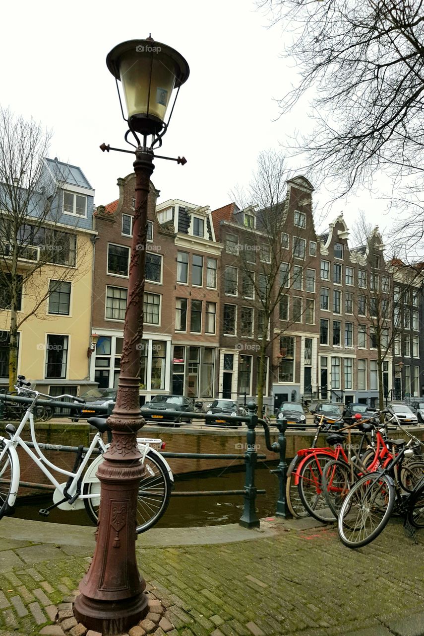 Vintage architecture roofs on buildings on an old alley street along canal with bicycles and street lamps in Amsterdam, Holland, Europe.
