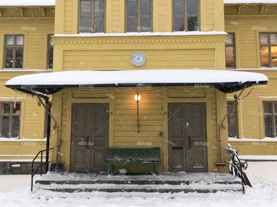 Entrance to an old yellow school building covered in snow