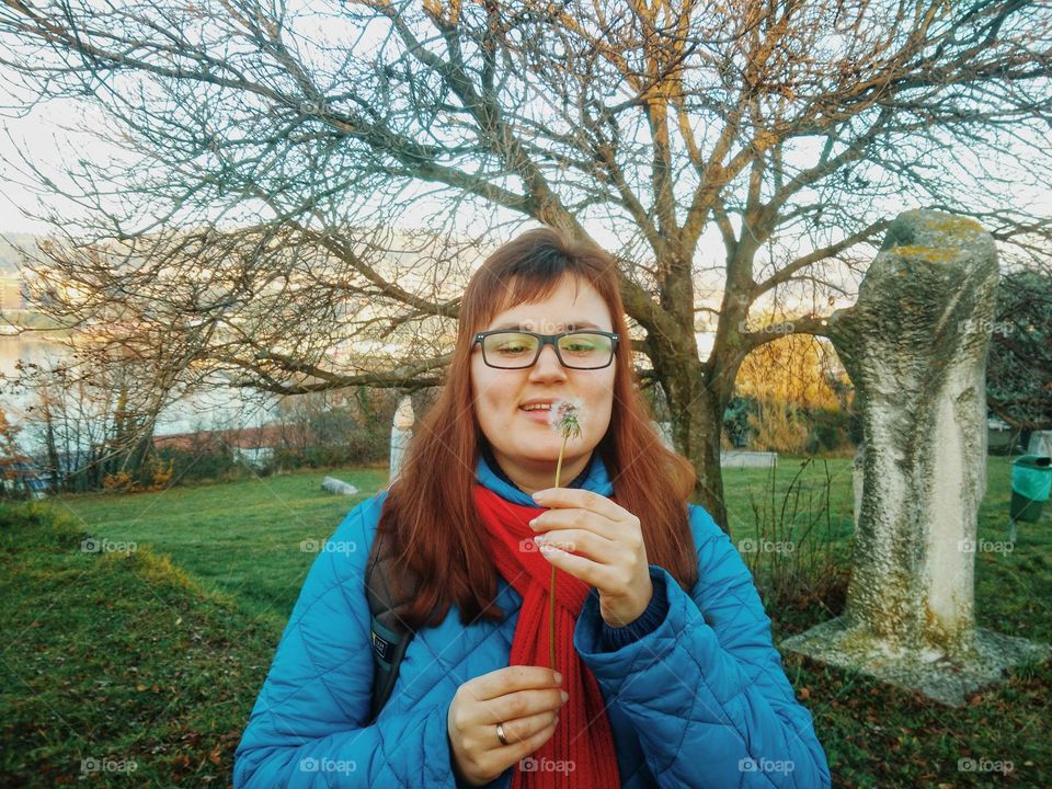 Portrait of young happy beautiful woman with dandelion flowers close up.
