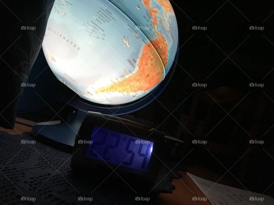 Late evening, with the globe in the background, lighting up my night table. My clock lights up the numbers 22:54, which is almost 11pm.