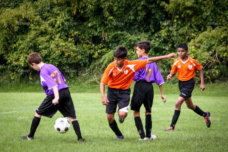 Teens are playing soccer outdoors