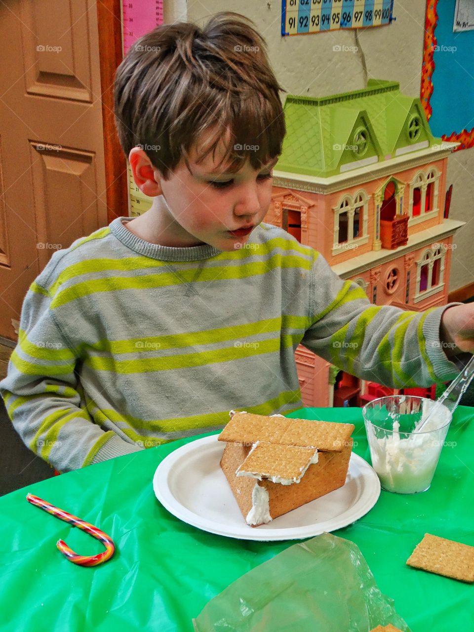 Young Boy Making A Christmas Gingerbread House
