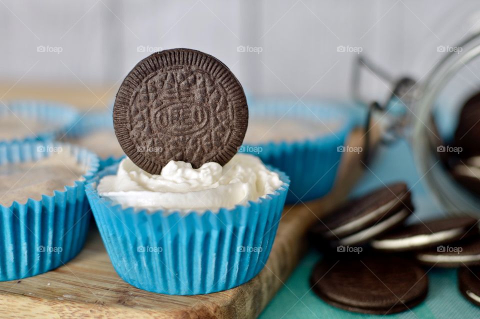 Oreo cookie ice cream cupcakes on a wooden board and white and blue background 