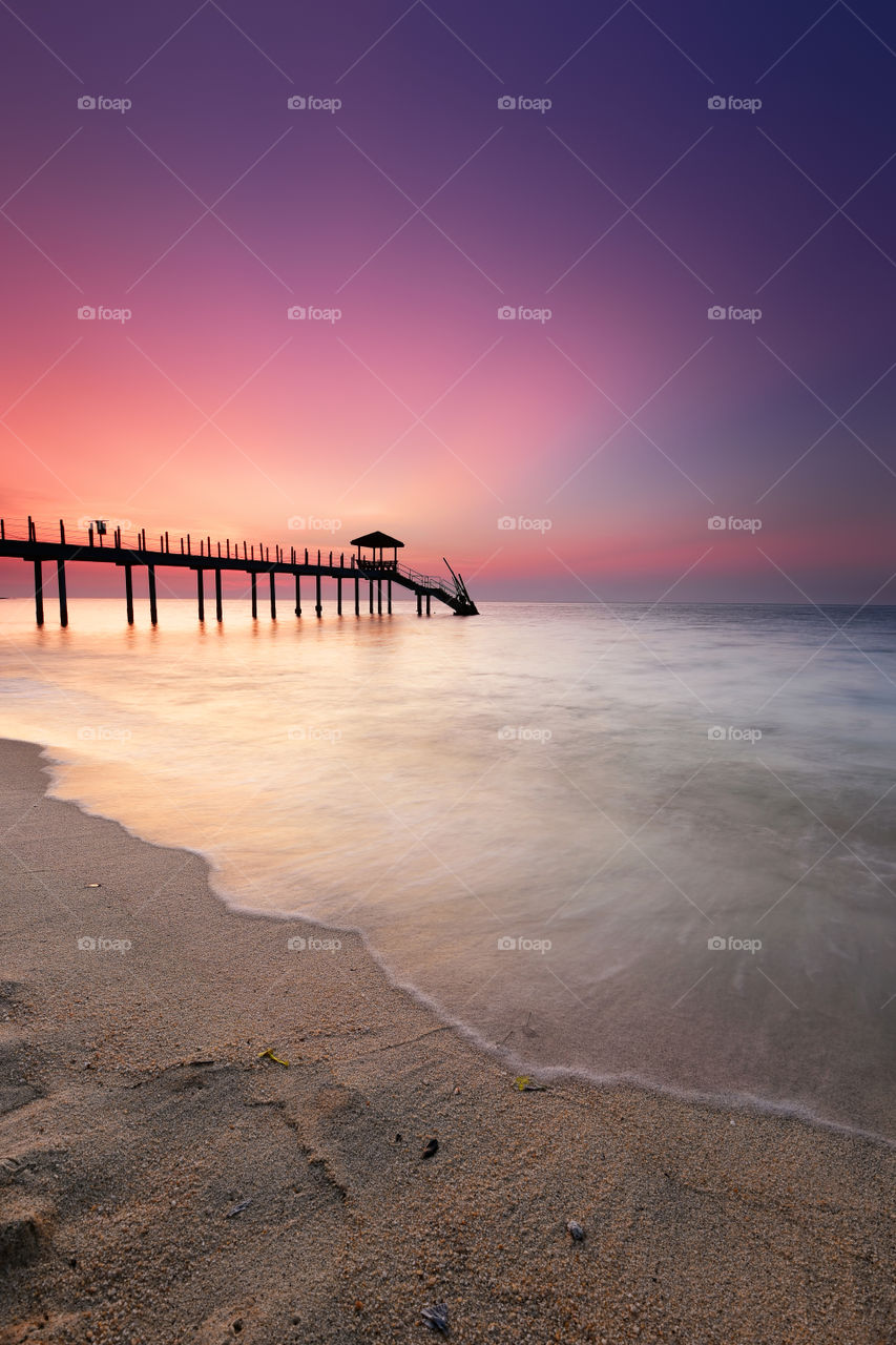 Jetty and beach on sunset background