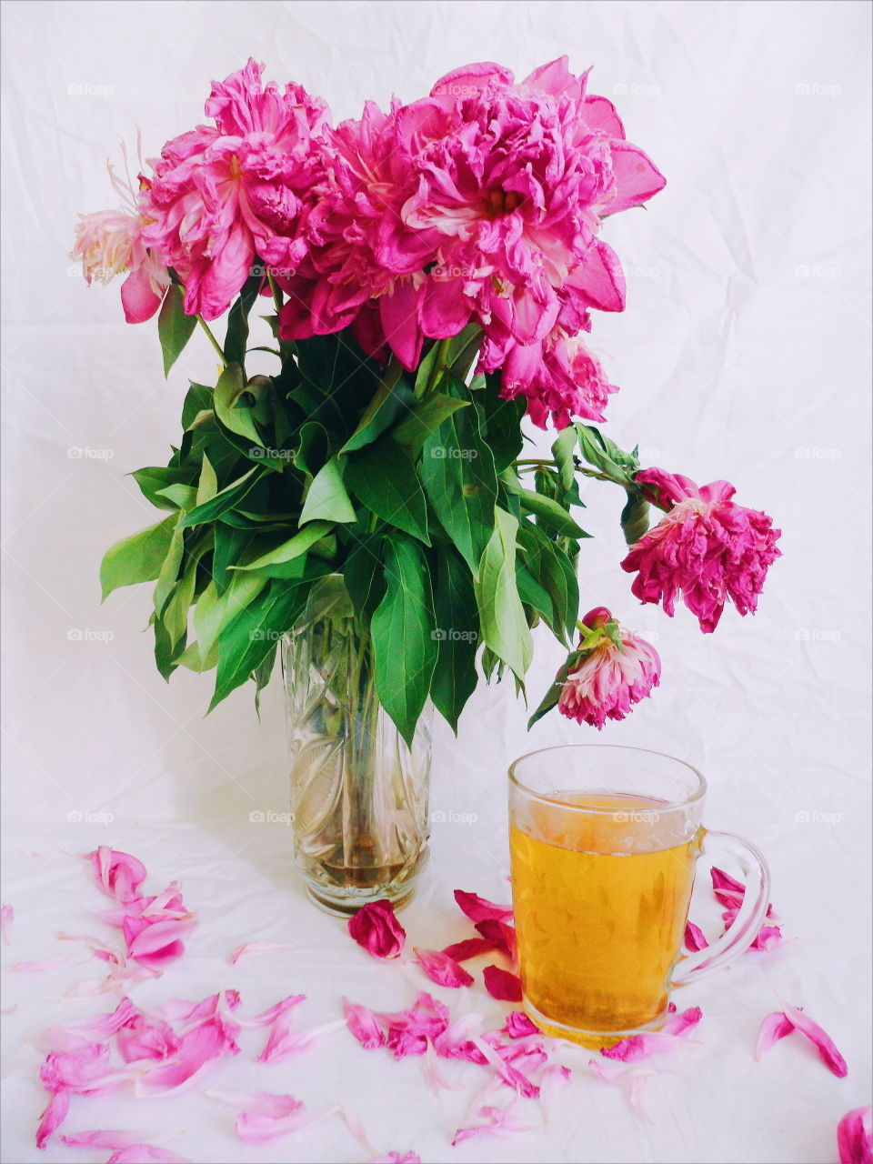 pink bouquet of wilted peony flowers and a cup of green tea