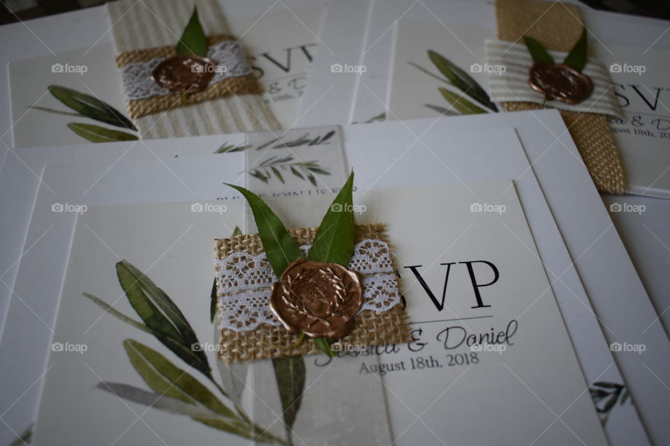 Custom wedding invitations with rose gold wax seals and leaves fix a ribbon that ties the invitations together. Natural tones and white. 