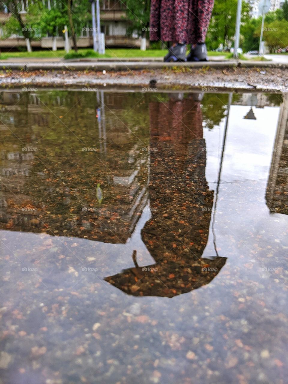 reflection in a rain puddle of a girl under an umbrella