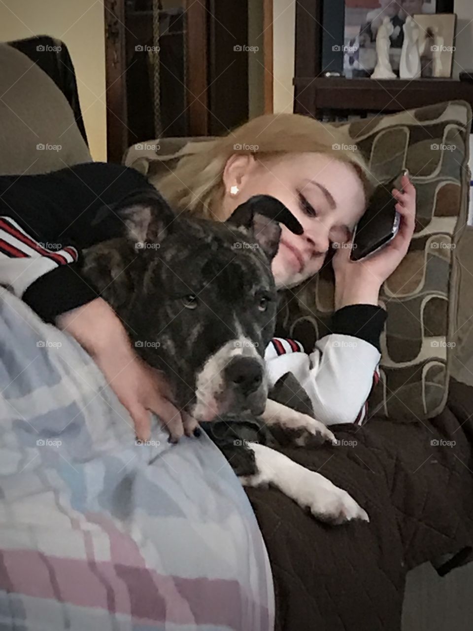 Woman sleeping on bed and mobile phone in hand with dog