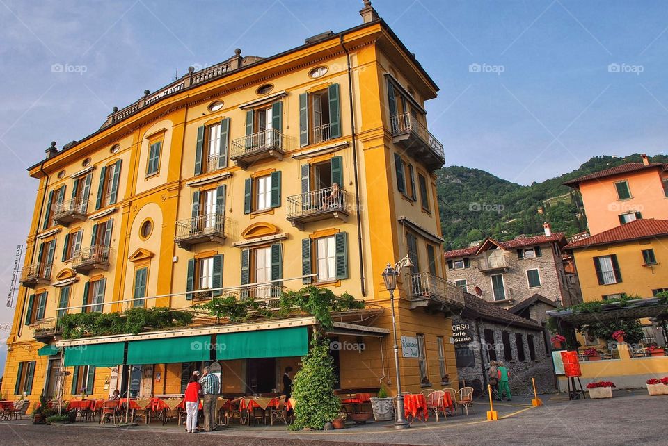 Golden hotel . A bright gold historic hotel with green shutters overlooking Lake Como in Bellagio Italy 