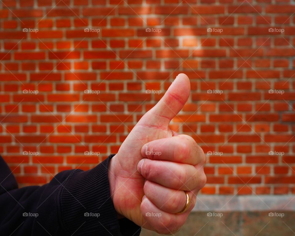 Thumb up in front of a wall