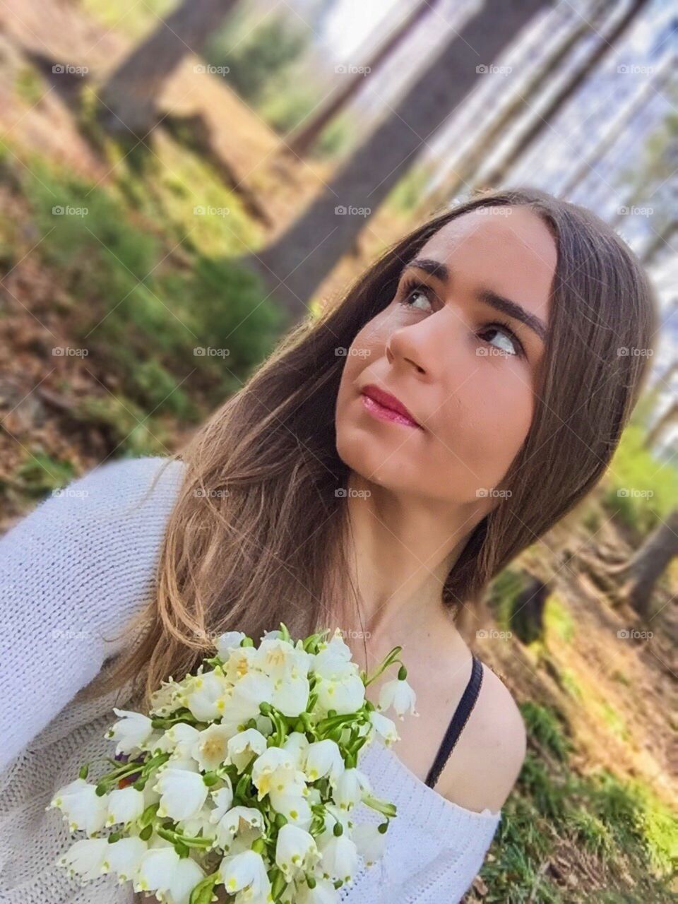 Portrait of sad woman in the forest holding a snowdrops bouquet