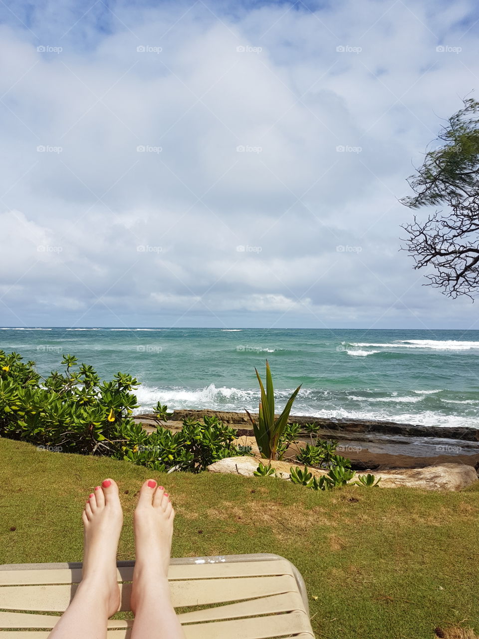 feet relaxing with view of Hawaiian ocean beach on cloudy summer vacation day