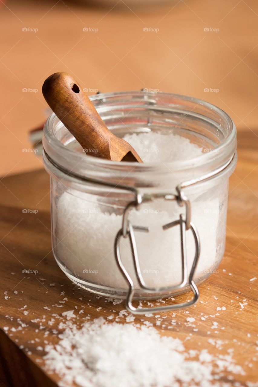 Sea salt in jar. Sea salt in a jar with a wooden scoop and spilled salt