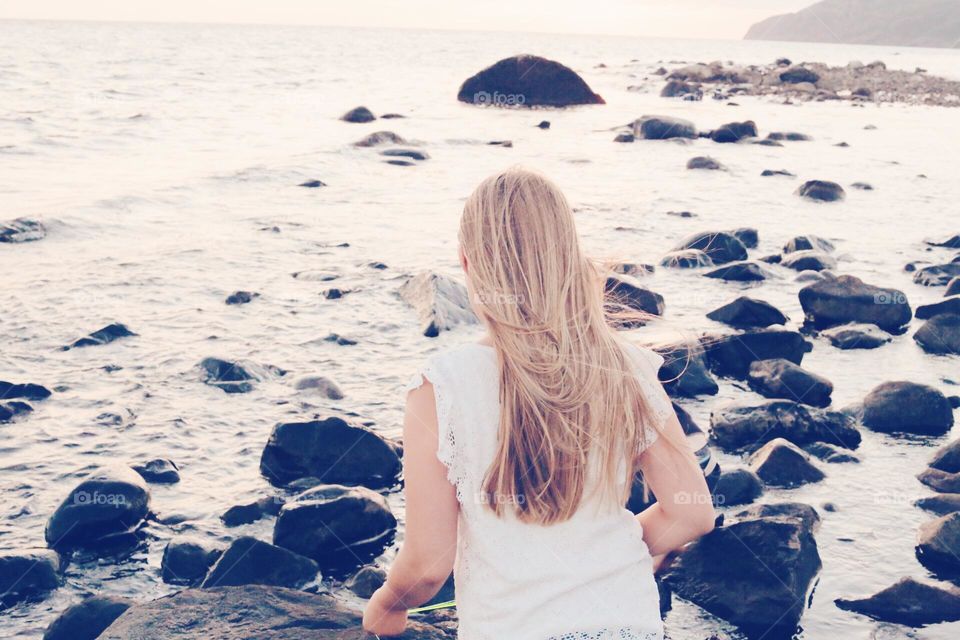 Blonde haired girl standing by the sea 