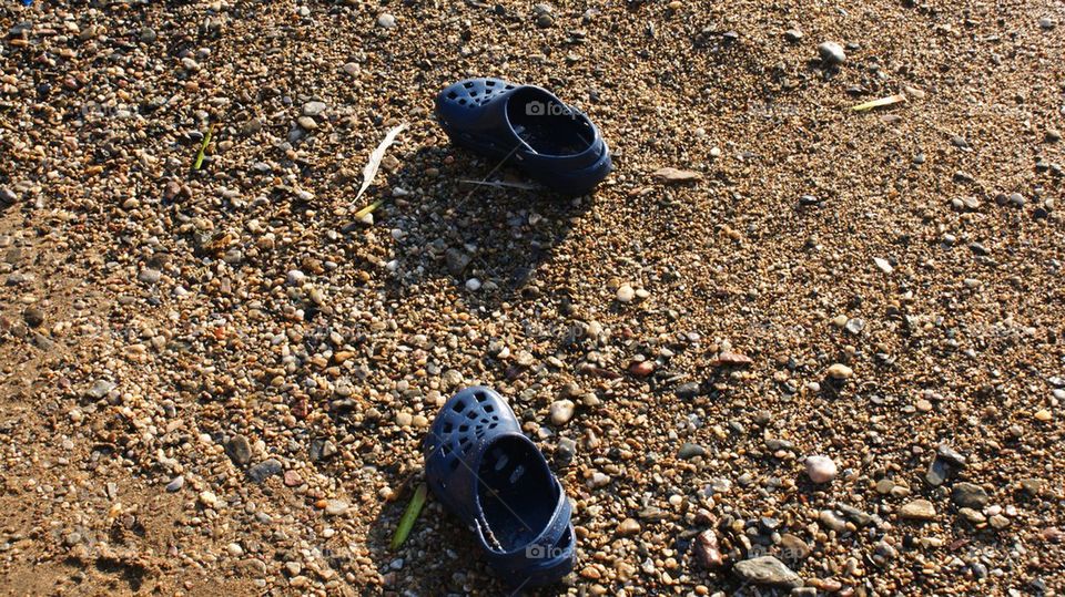 Baby shoes on a pebble beach.