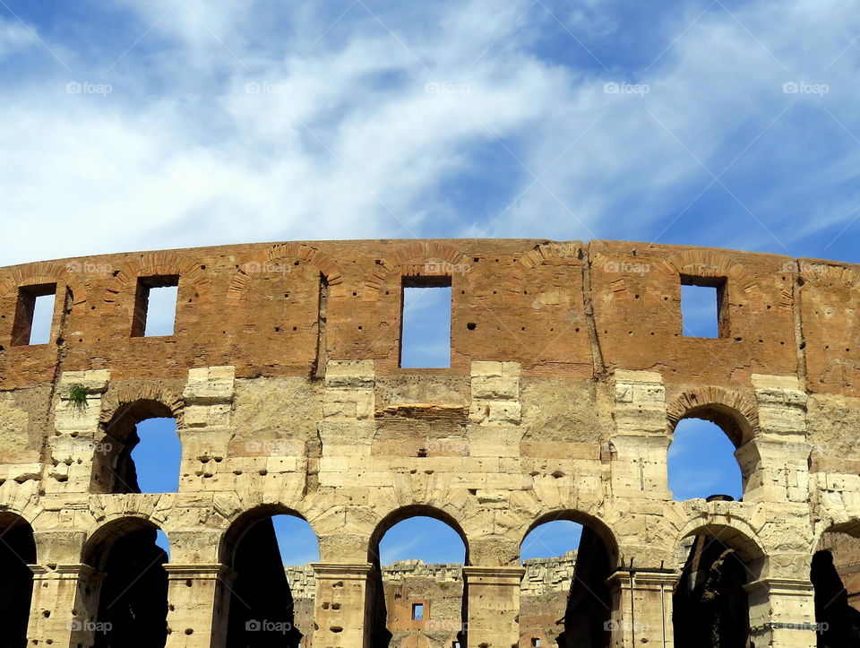 view under the blue sky of the Colosseum walls in rome