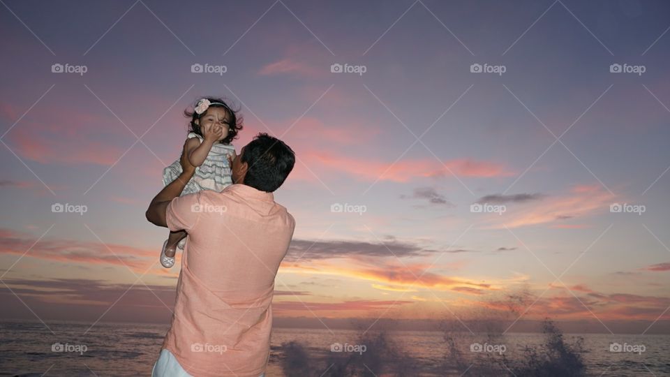 Father raise her daughter to the sky as she shines.