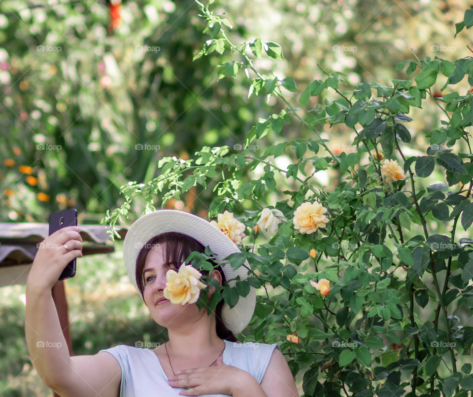 One young woman take photo with flowers.