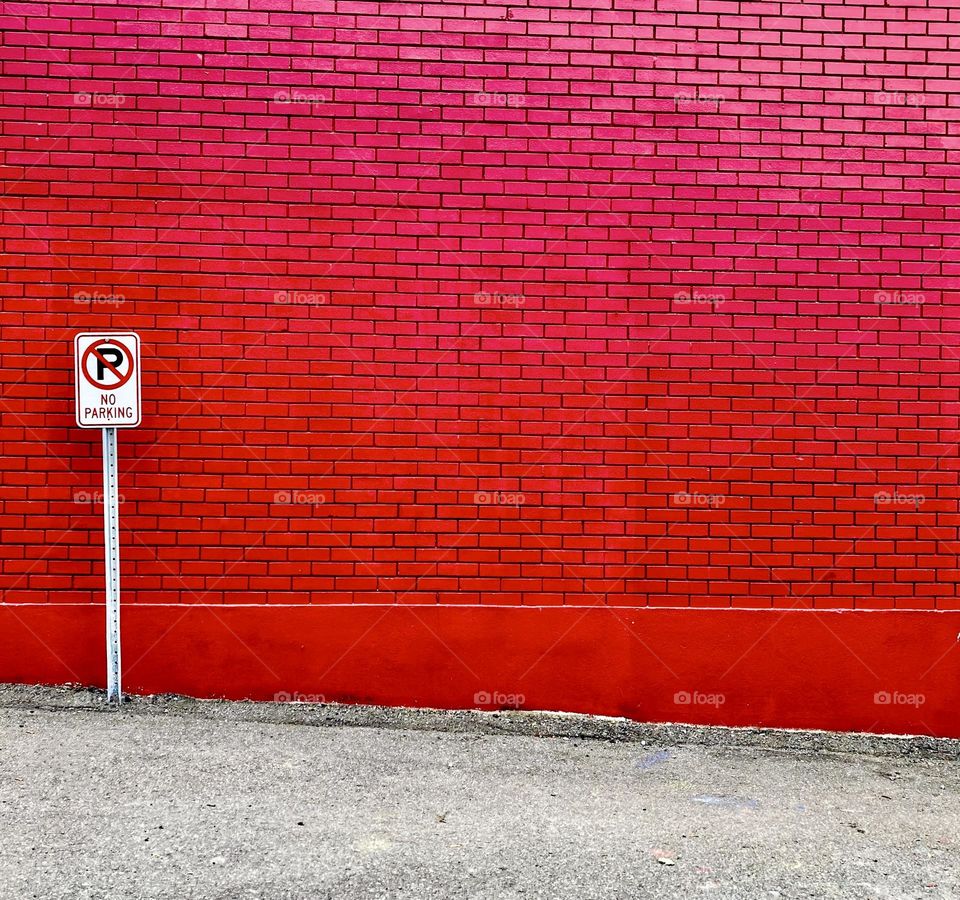A Christmas red brick wall with a No Parking sign.