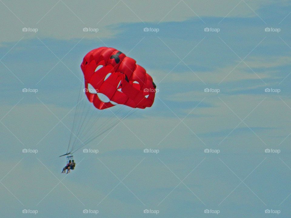 Color Red - Parasailing is an exciting and thrilling activity where people glide through the air in an open parachute while being pulled by a boat