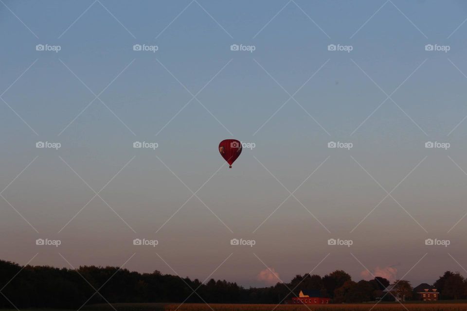 Hot air balloon high in the sky, above the meadows
