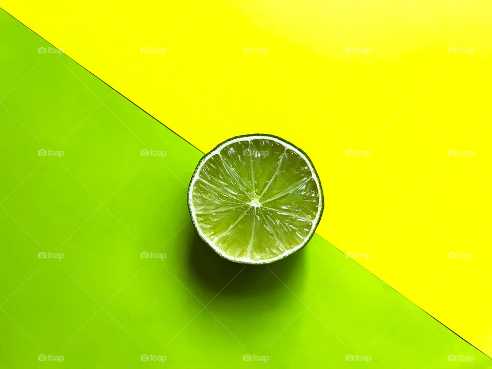 Slice of lime on green and yellow background 