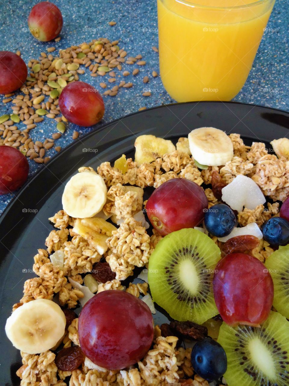 Healthy breakfast of crunchy flakes kiwi, banana, grapes, berries, raisins and fresh orange juicy drink