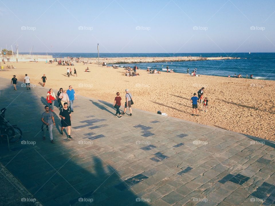Looking down on the promenade or walkway at El Poblenou beach in Barcelona Spain at people walking and enjoying sunset 