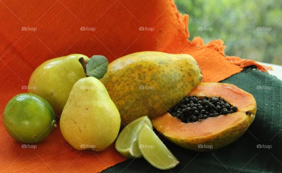 Papaya, pear and lemon on an orange and green background