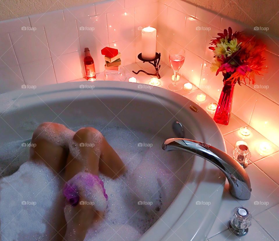 Woman taking a luxurious bubblebath by candlelight.