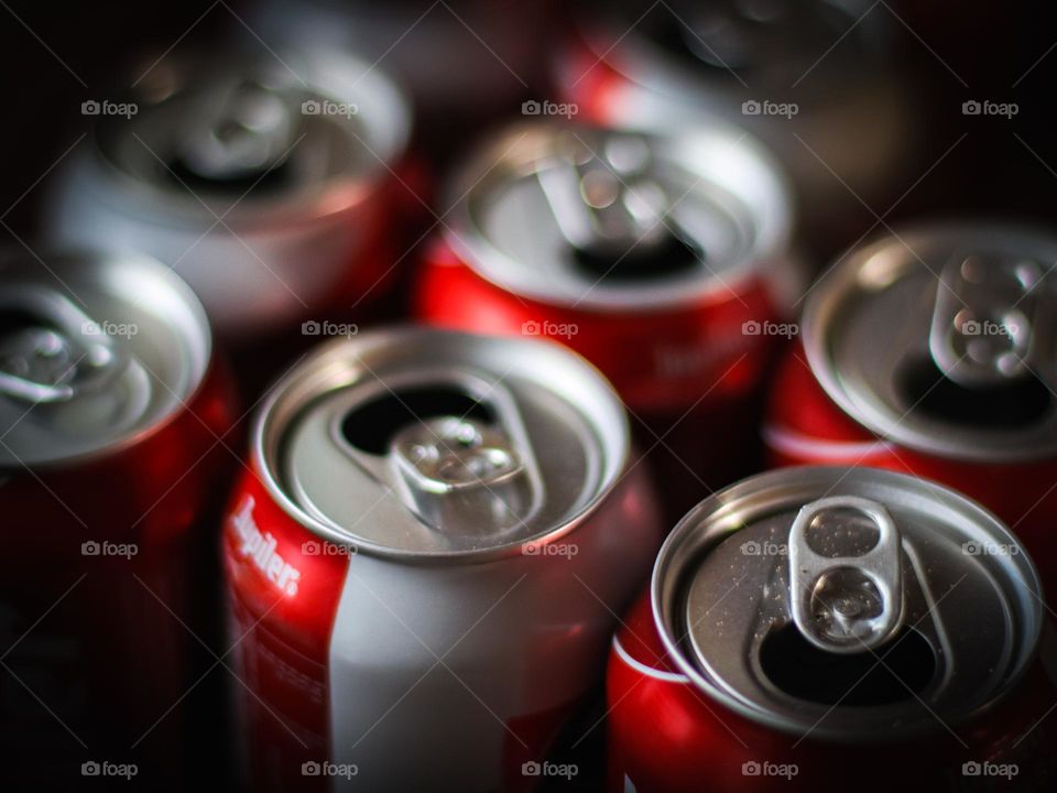 Empty used metal cans from Belgian beer brand jupiler stand in three rows on a table with selective focus in daok style, close-up. Metal concept, depth of field.