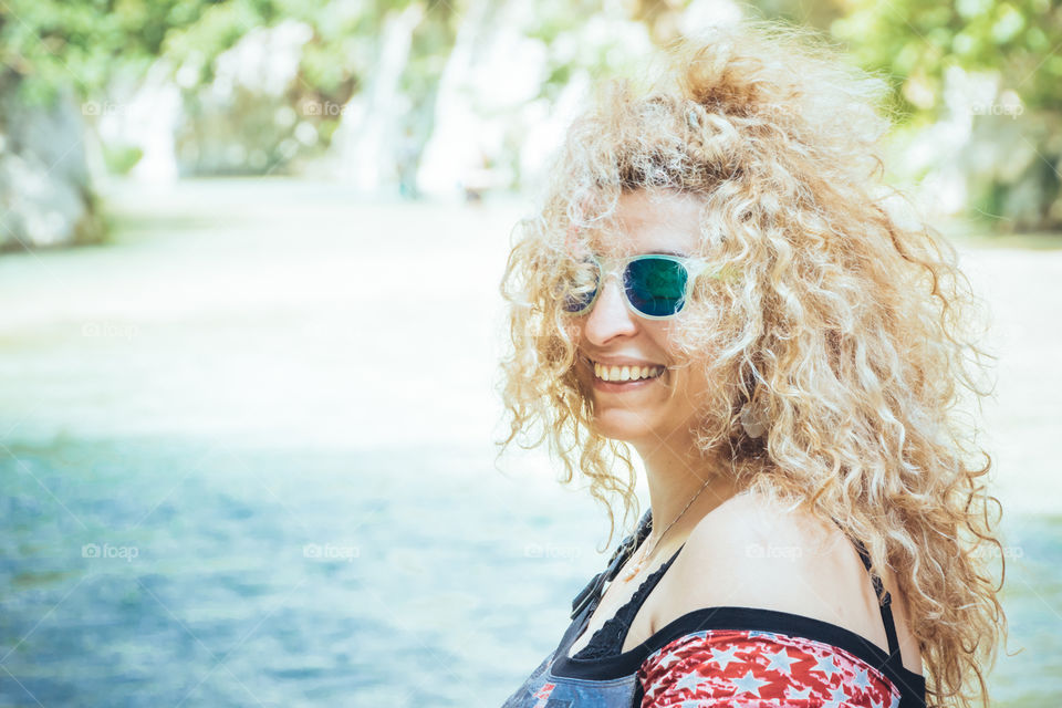 Happy Blonde Woman With Mirrored Sunglasses On Vacation During Daytime
