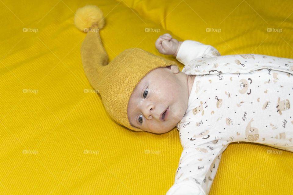A newborn baby on a yellow and gray background. A photo shoot in the style of Newborn and lifestyle.