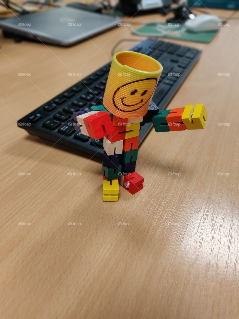 Smiley emoji man on the office desk by the laptop and keyboard