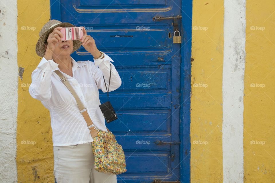 A traveler taking photos with her smartphone and a camera hanging from her elbow in Essaouira, Morocco