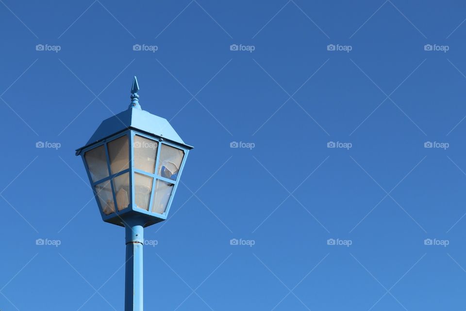 Blue street Lantern with broken glass against vivid blue sky minimalist image room for text 