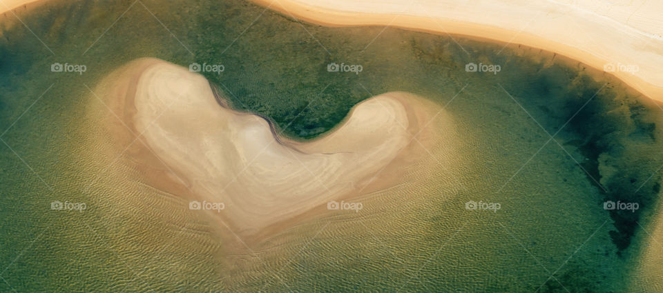 Aerial view on a island in the ocean in shape of heart. Panorama view.