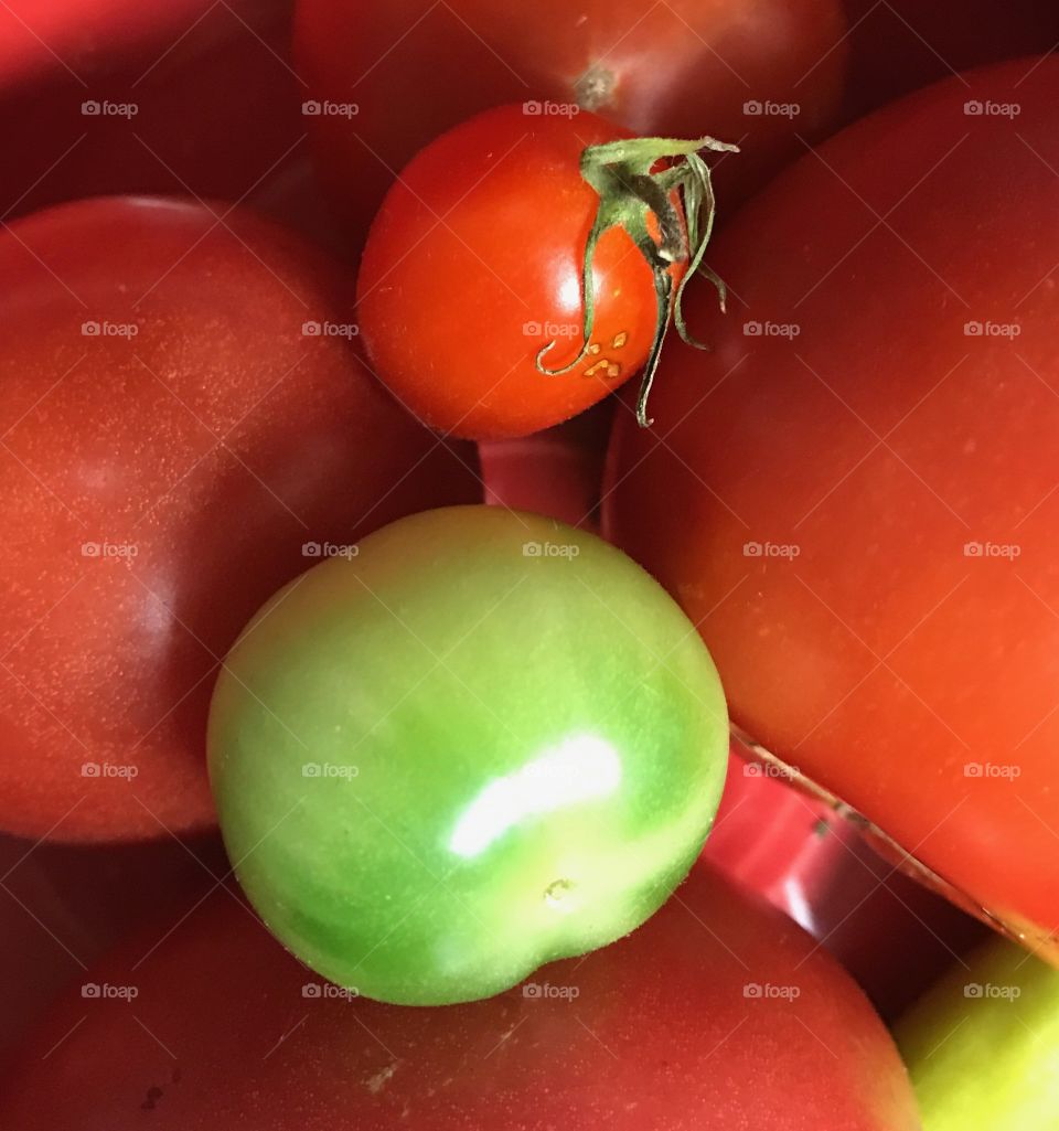 Bowl full of tomatoes that are at various stages of ripeness 