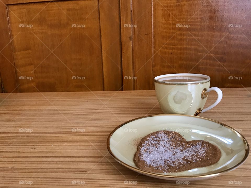 Cup of nes coffee with a plate of nes coffee and sugar made in a shape of heart.