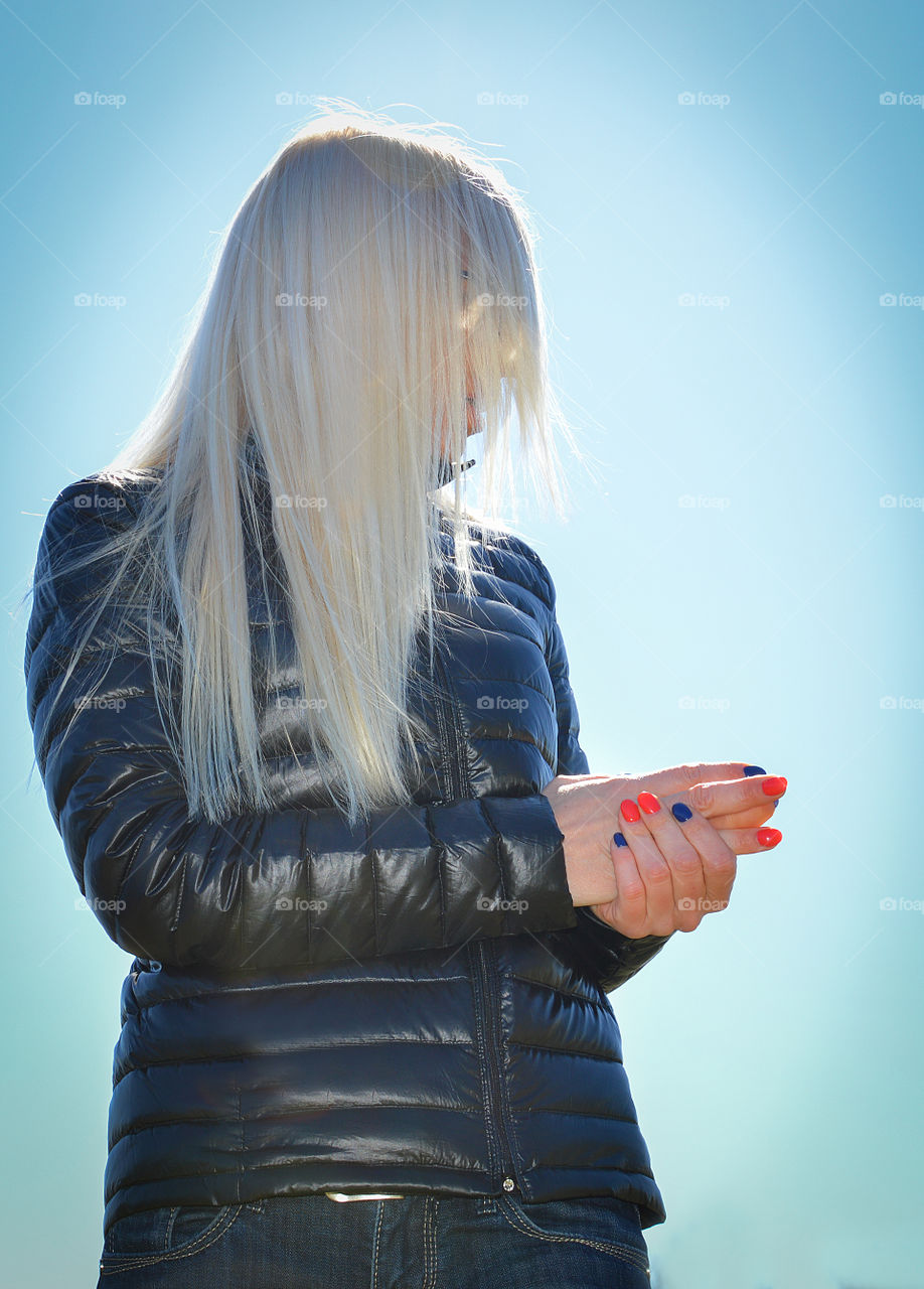 Blond woman eith streight hair on blue sky background