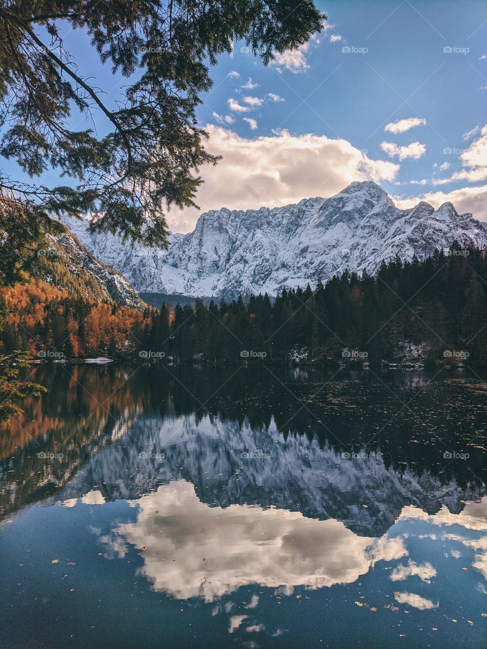 View of the autumn snow-capped mountain peaks against the backdrop of a transparent Italian lake.