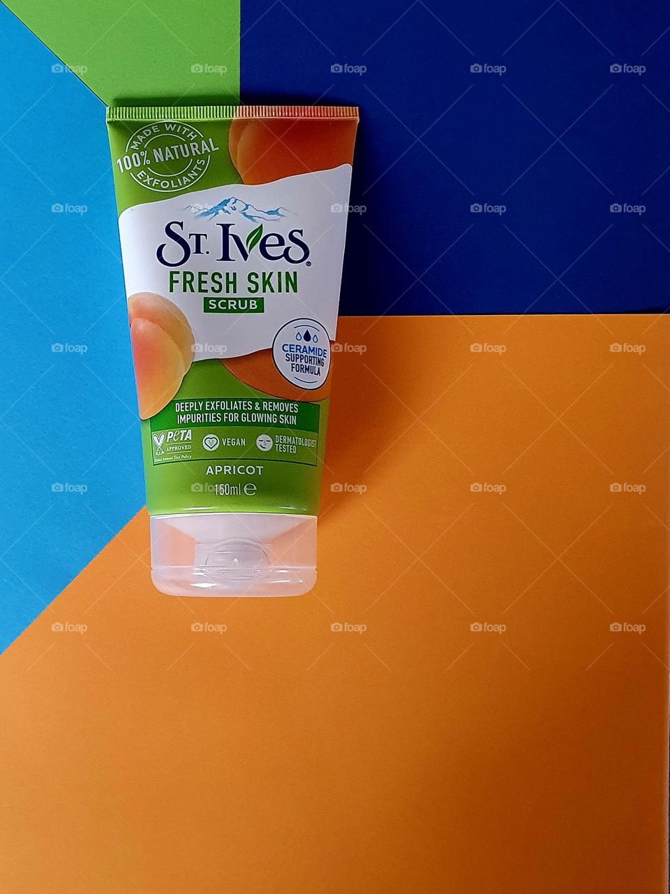 Flatlay of St Yves Fresh Skin Scrub placed on light blue, navy blue and orange papers forming a geometrical pattern
