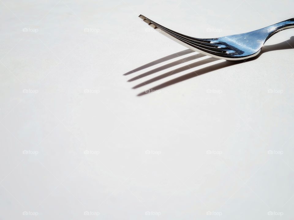 fork and its shadow on white background