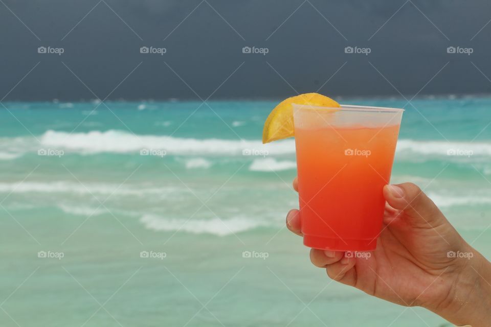 cold orange drink in caribbean beach with sthorm in the horizon