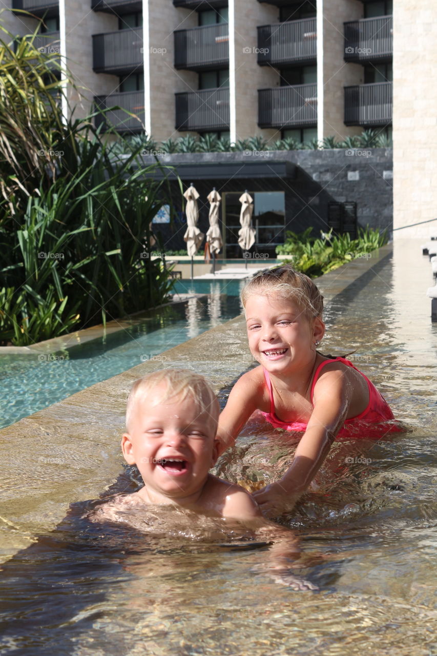 Cute blonde siblings having fun at the pool 