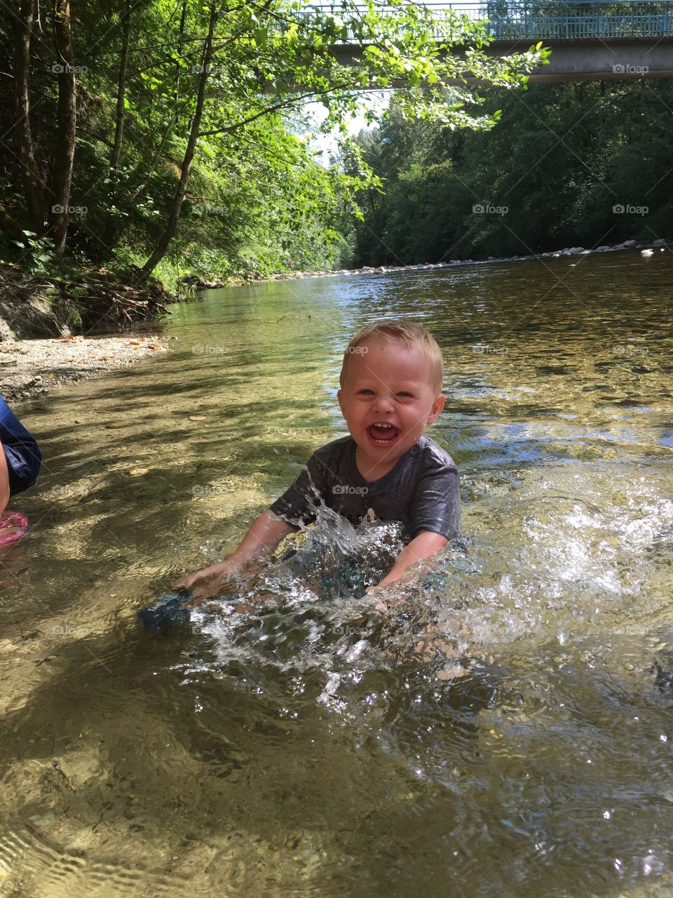 Toddler boy playing in river so happy