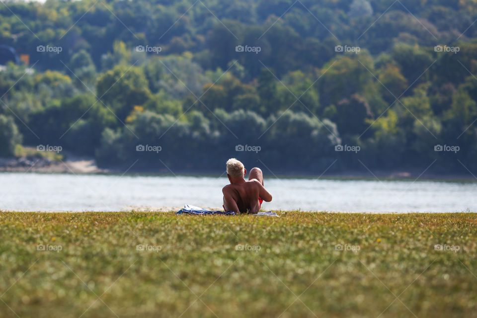 Elder man enjoying last summer days on the river beach