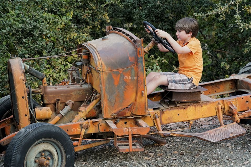 Young Boy Riding An Old Tractor