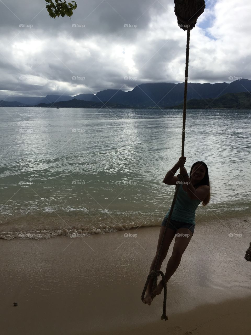 Girl on rope swing at beach