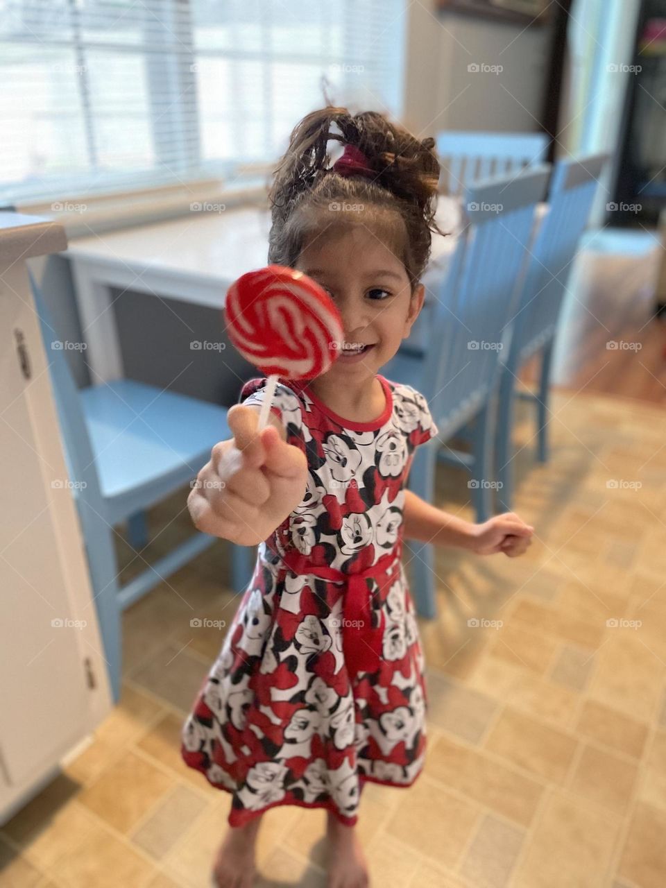 Toddler girl with sucker for Valentine’s Day, celebrating with suckers and candy, little girl excited about candy, eating candy for Valentine’s Day